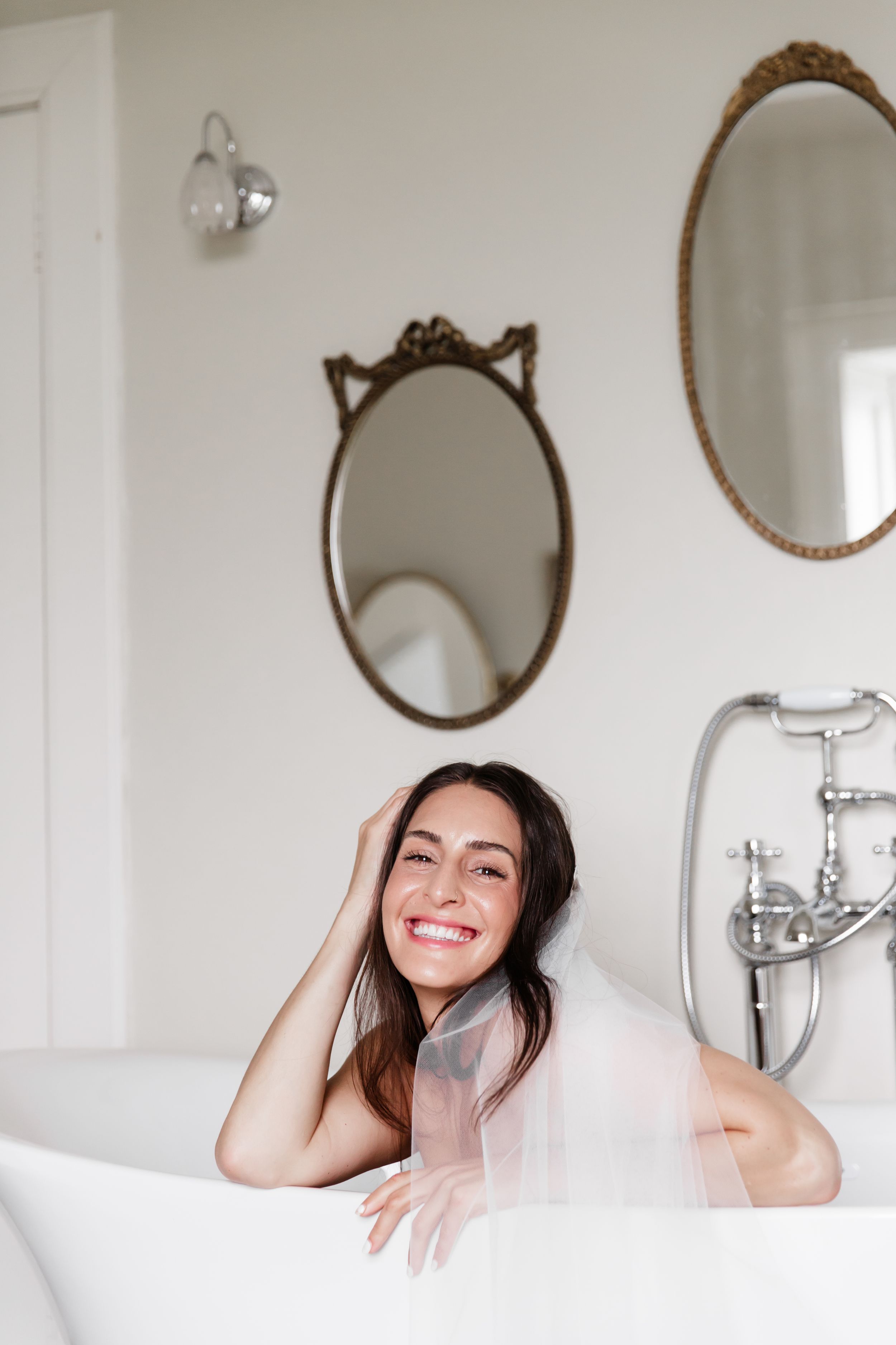 Relaxing bath scene with vintage oval mirrors and white clawfoot tub in a bright minimalist bathroom.