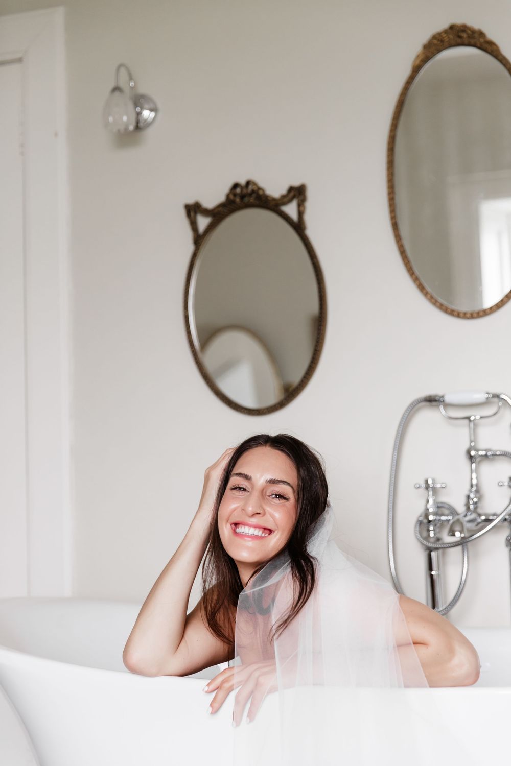 Relaxing bath scene with vintage oval mirrors and white clawfoot tub in a bright minimalist bathroom.