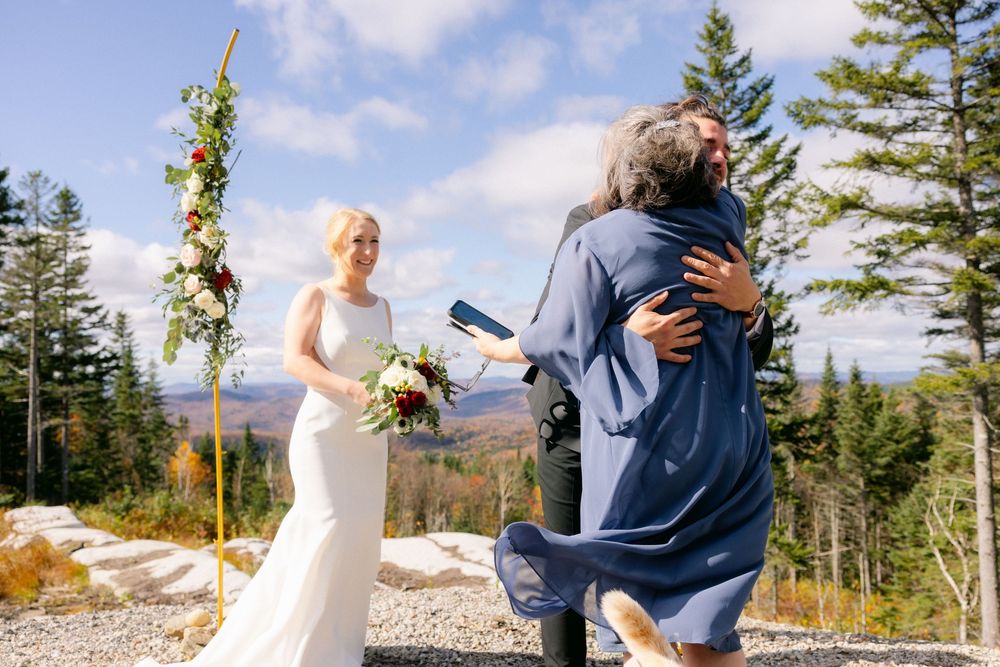 A couple shares romantic moments during their mountain wedding ceremony against a scenic forest backdrop.