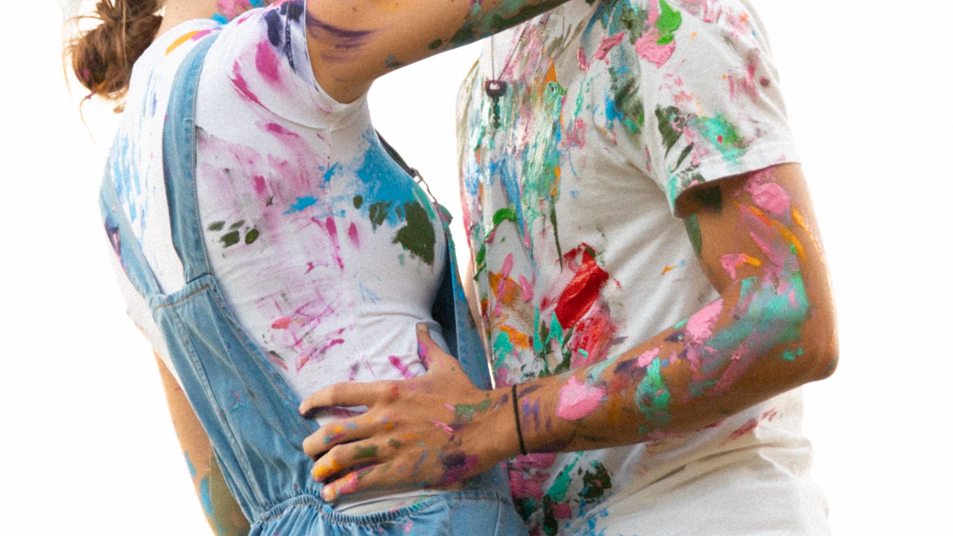 A person holding a colorful paint splattered tie dye shirt while creating artistic designs.