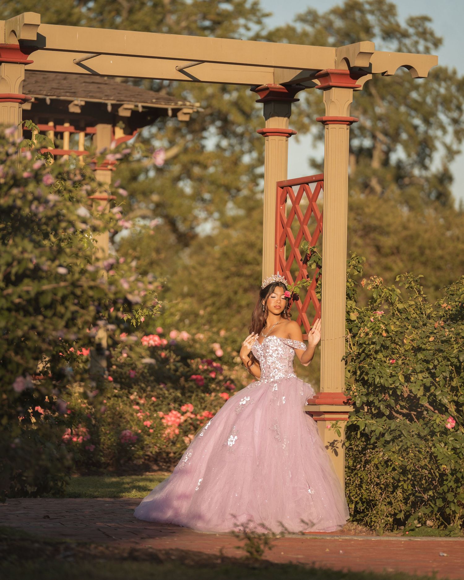 A series of sunset photos showing a pink ballgown in a garden setting with wooden pillars and blooming roses.