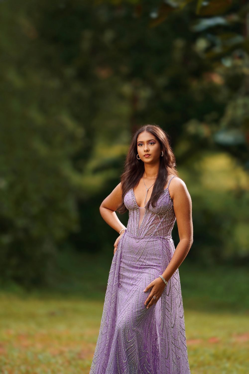 Elegant purple evening dress with delicate lace details photographed in a natural outdoor setting.