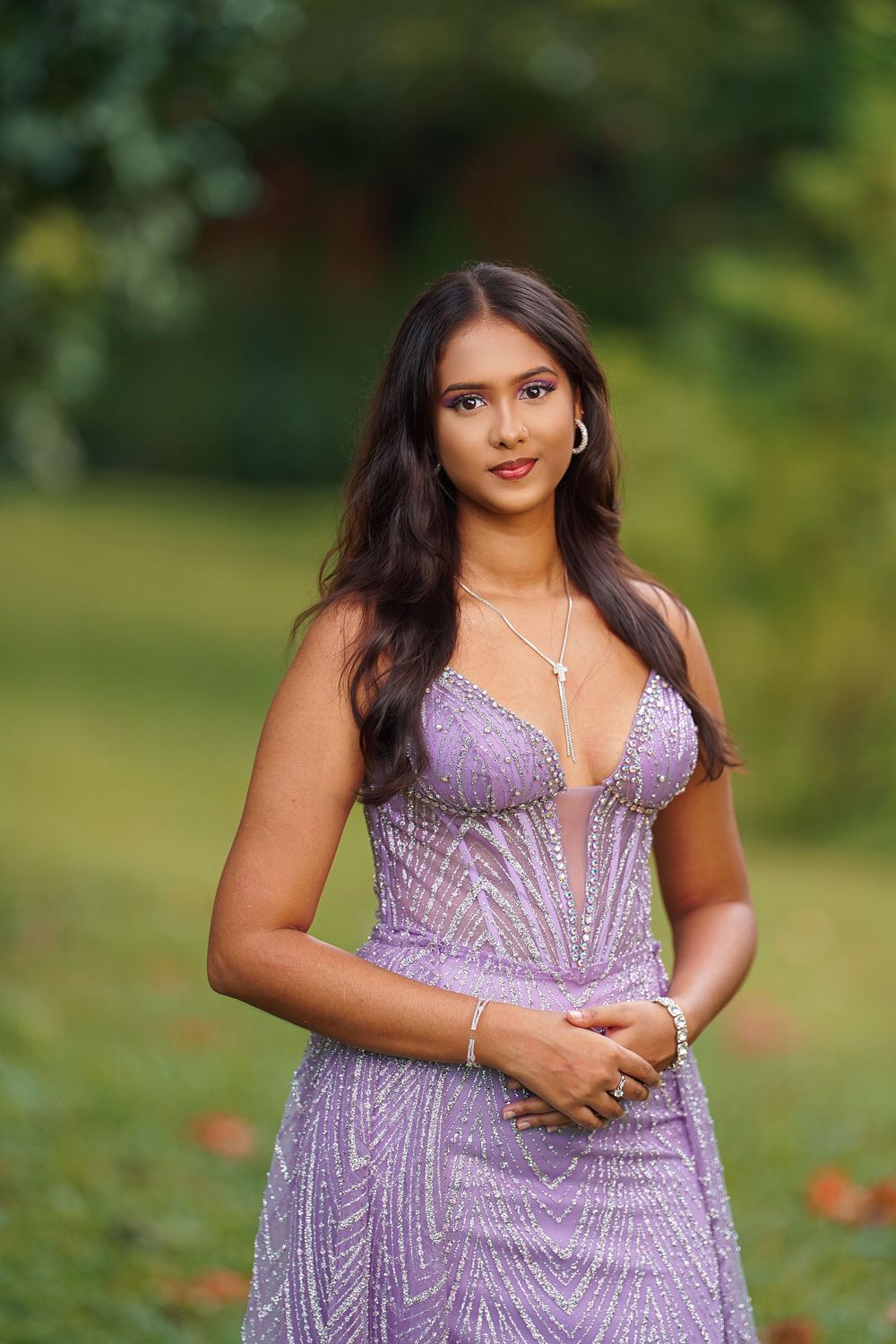 Beautiful lavender formal dress with beaded detailing photographed against lush green foliage.