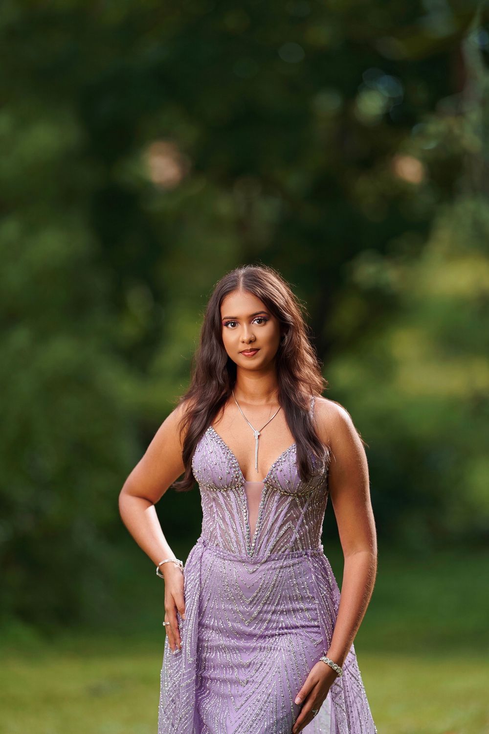 A stunning purple evening gown with intricate beading sparkles in natural outdoor lighting.
