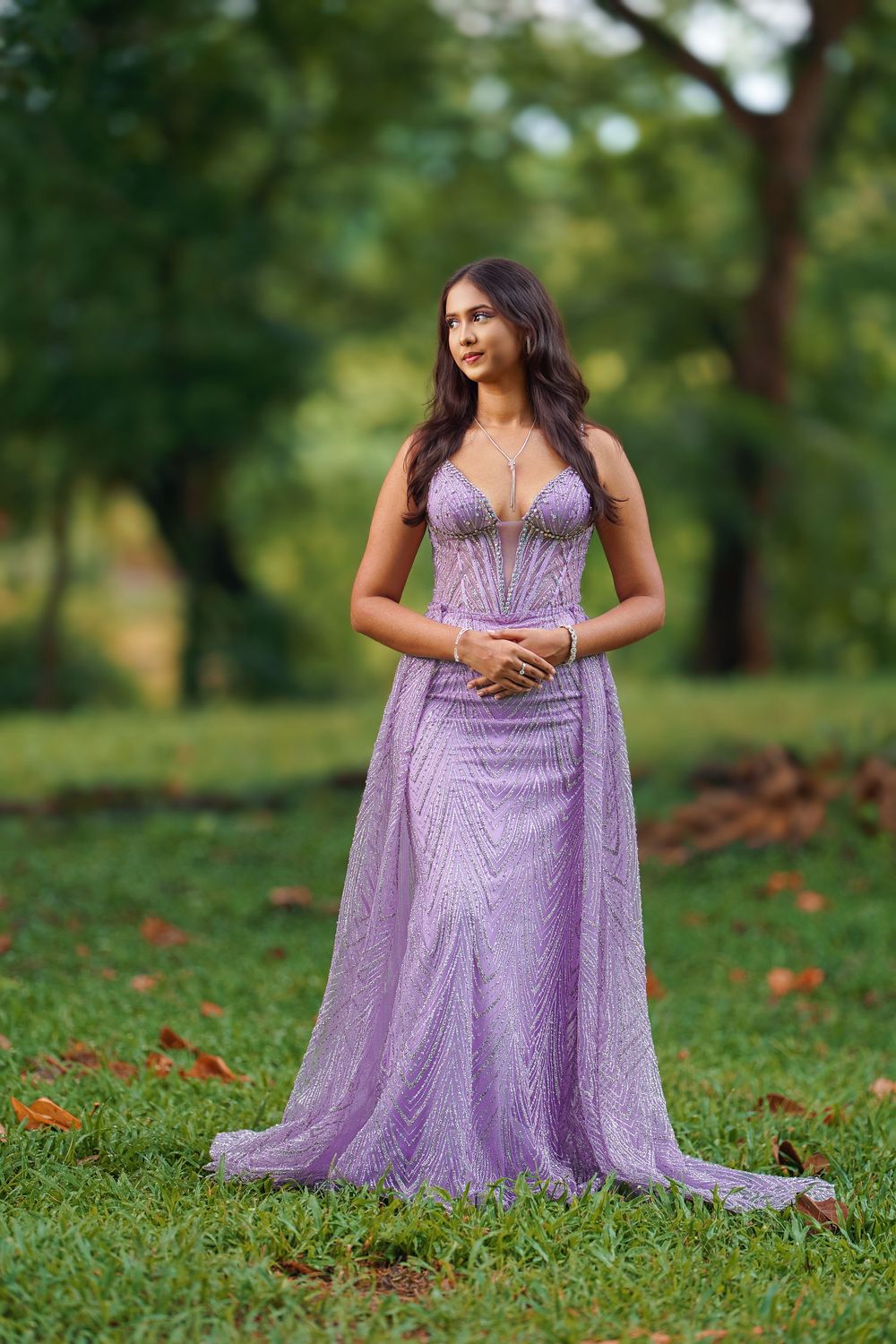 Ethereal purple evening gown with detailed beadwork showcased in a serene outdoor setting.