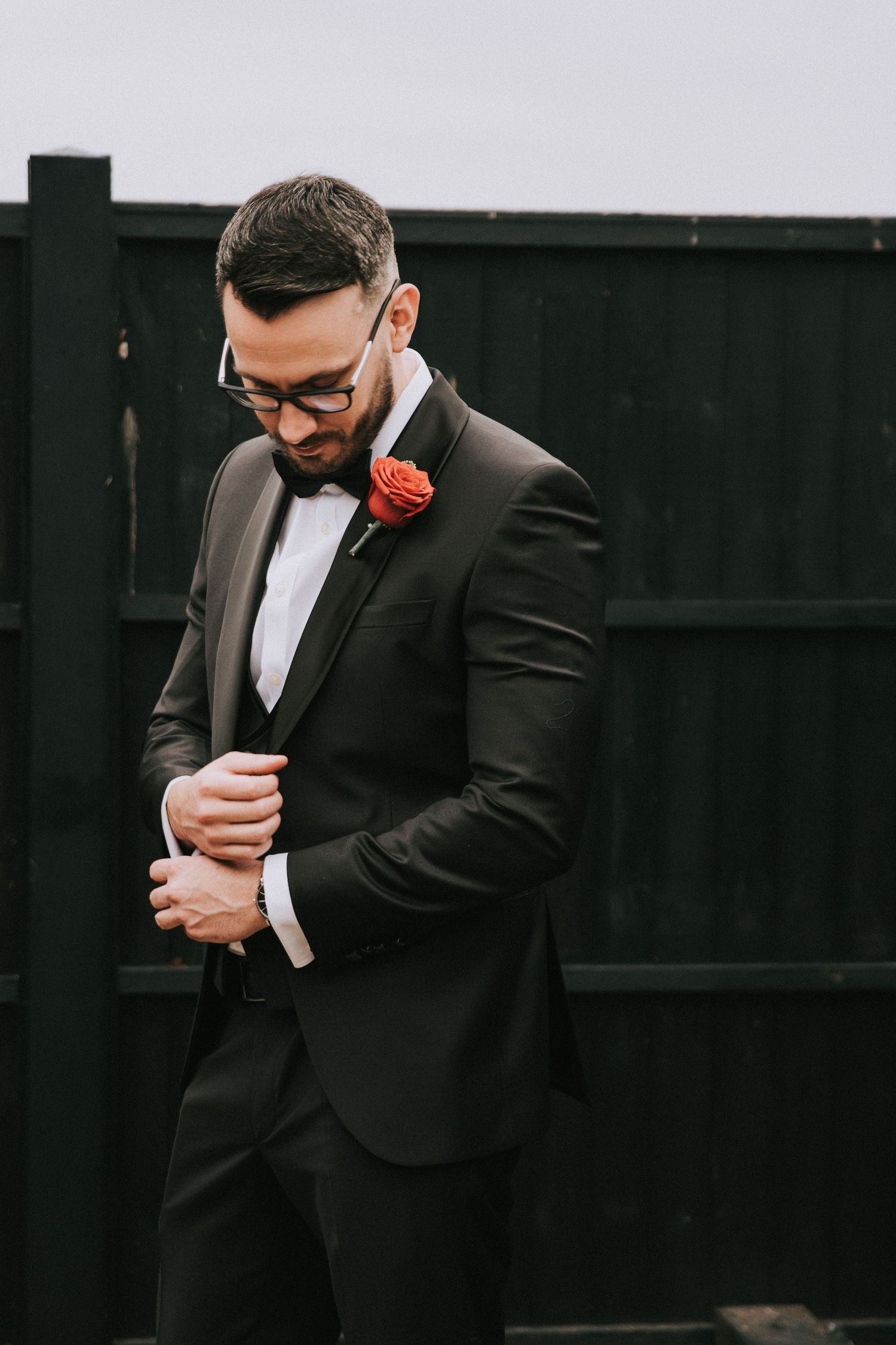 A person in a black suit adjusts their tie while looking down in a series of moody editorial-style photos.