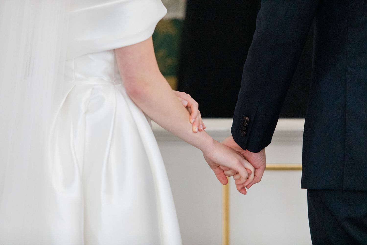 A couple in wedding attire hold hands while walking together on their special day.