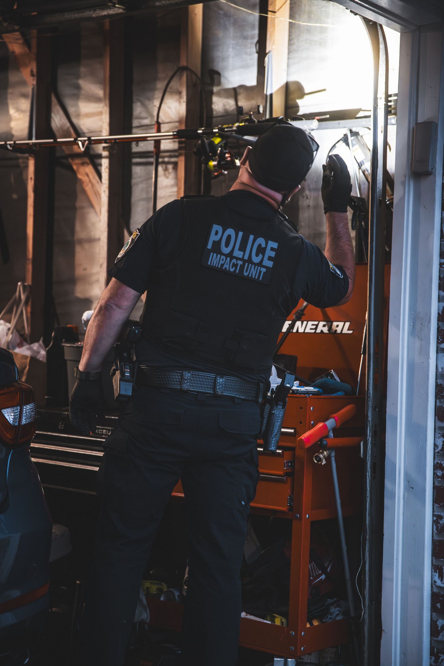 Police officers inspecting interior space with tactical equipment.