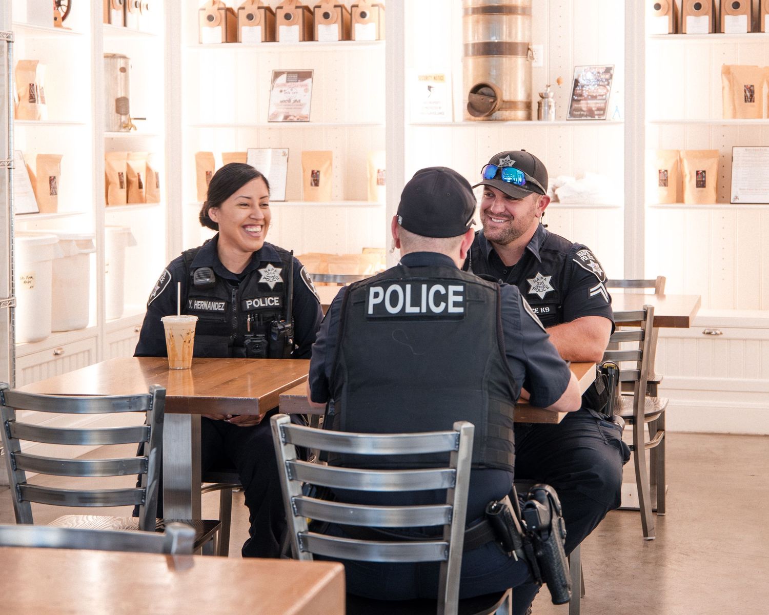 Police officers gathered around tables in a bright indoor coffee shop.