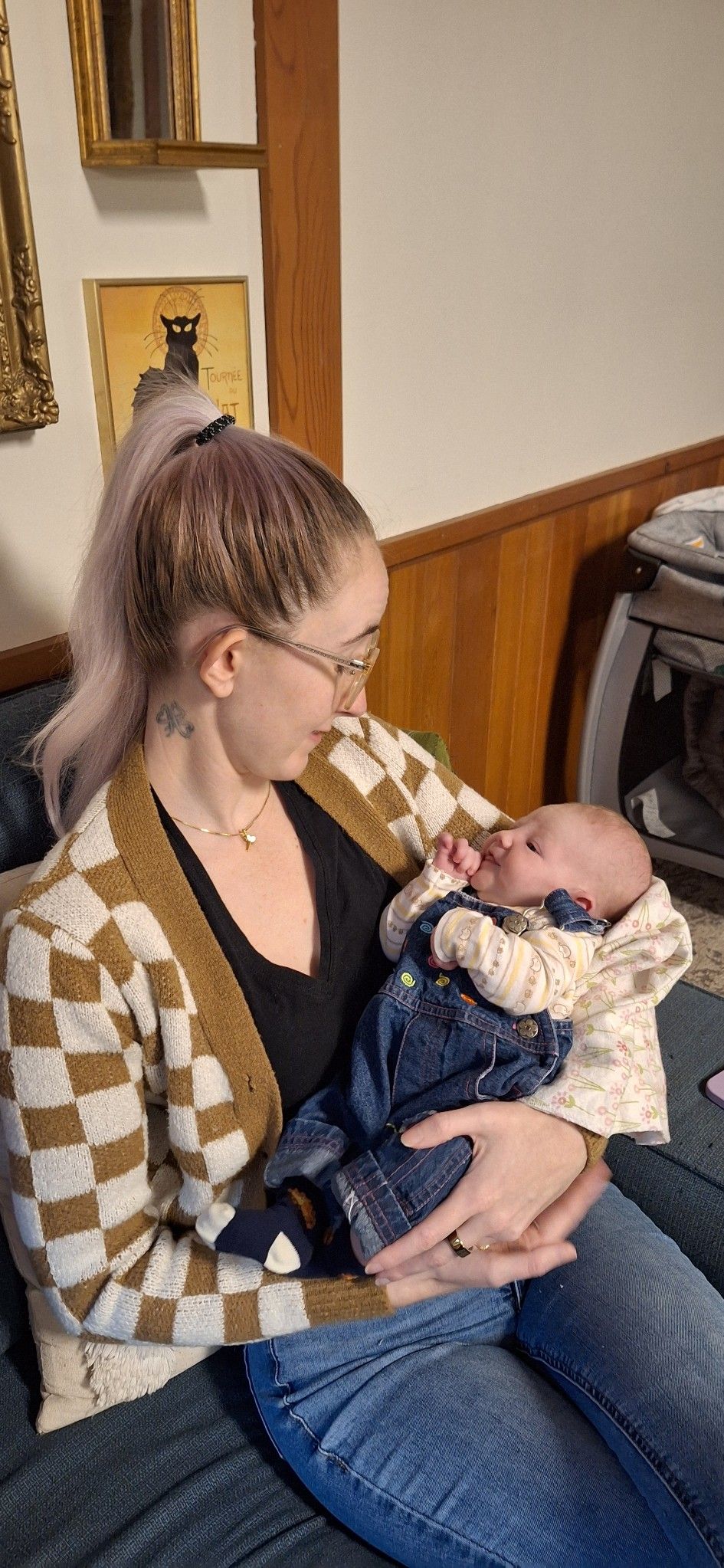 A tender moment of parent and baby in matching argyle sweater and overalls resting together on a couch.
