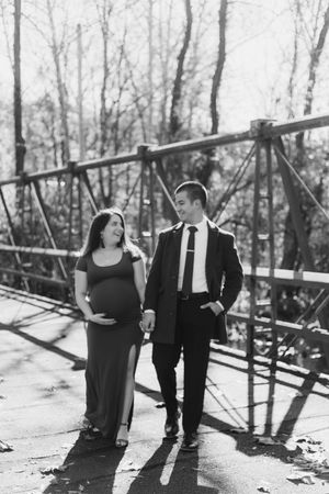 Two people share an intimate moment on a rustic bridge in a winter forest setting.