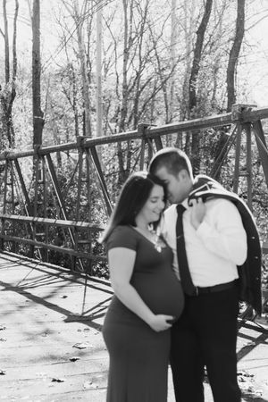 A couple shares an intimate moment while standing together on a snowy path surrounded by bare trees.