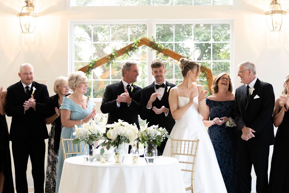 Wedding reception in an elegant indoor venue with white decor and formal attire.