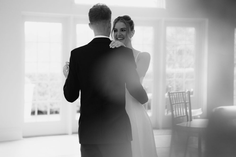 Black and white indoor wedding photos with soft window lighting.