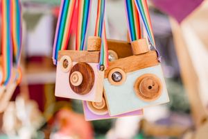 Colorful wooden toy cars hanging from strings in soft focus.