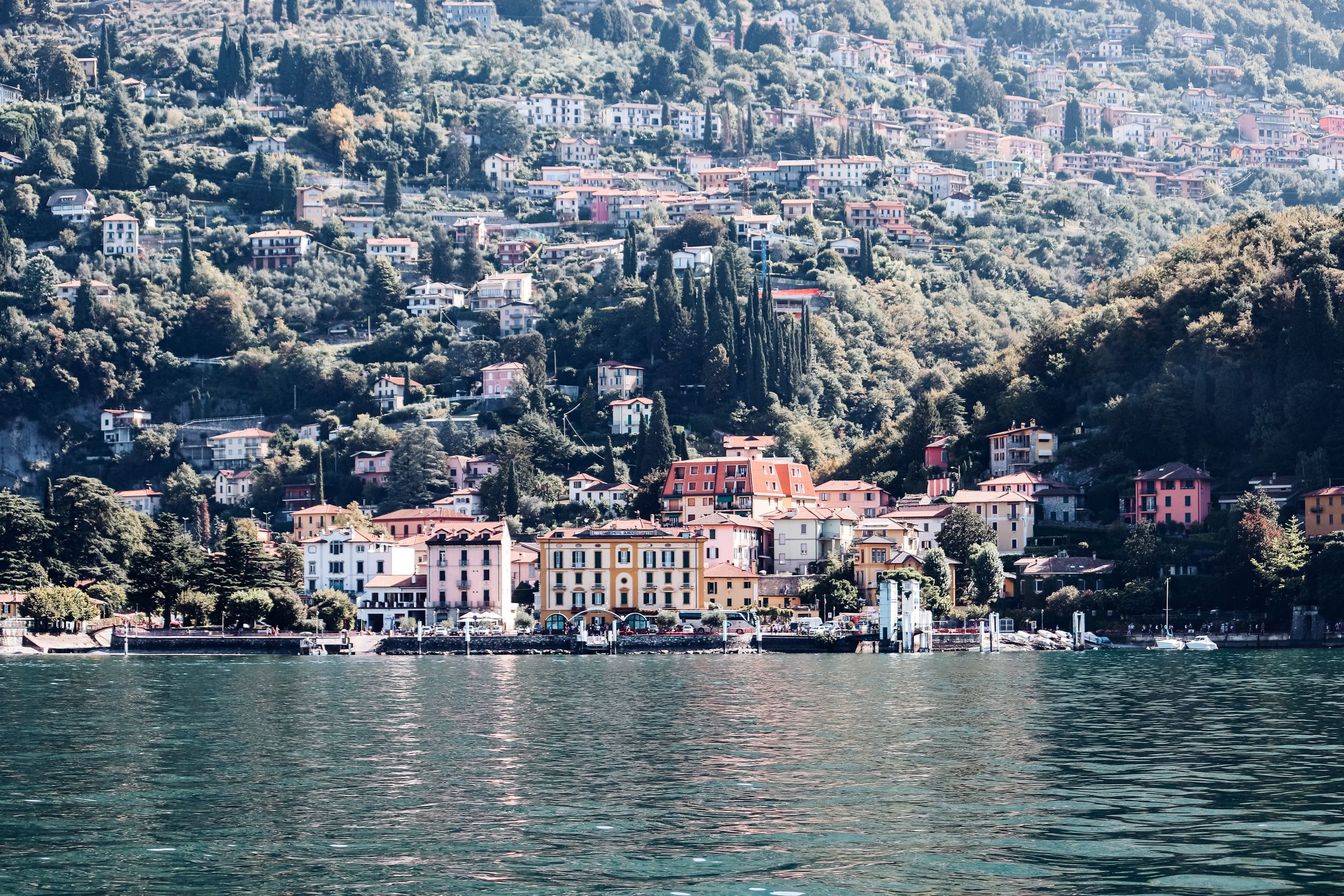 Scenic coastal town with colorful buildings nestled along a lake surrounded by mountains.