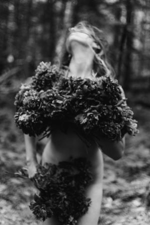 Black and white close-up photo of kale leaves growing in garden pots with a blurred forest background.