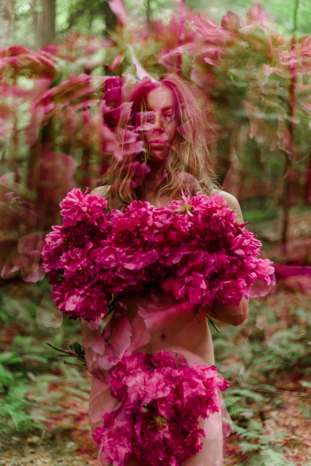 Abstract motion blur photograph of pink flowers in a forest with ethereal dreamy effect.