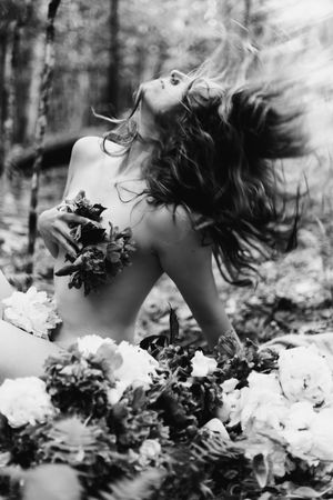 A series of black and white photos showing a person lying in flowers with windswept hair creating a dreamy effect.