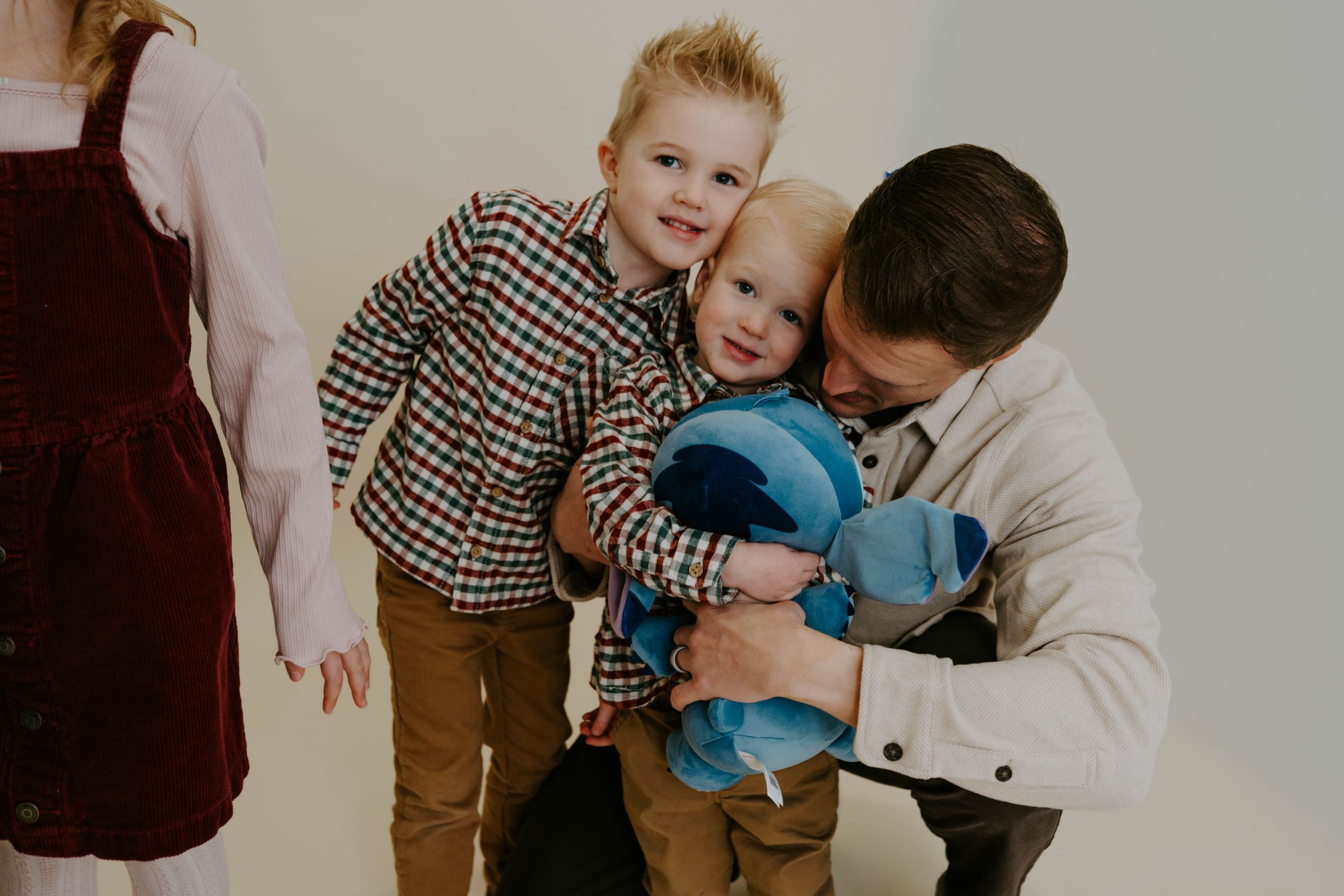 A heartwarming family moment captured during a professional photo shoot against neutral backdrop.