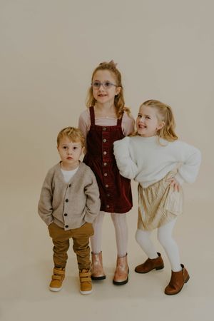 Three young children posing together in coordinated casual outfits for a portrait.