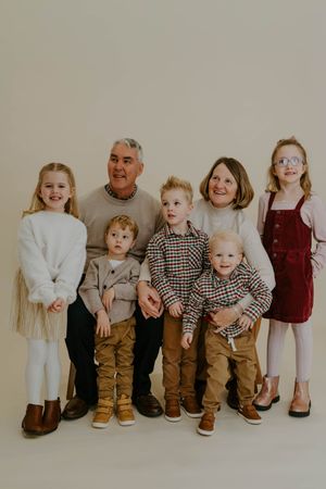 Studio family portrait with everyone wearing coordinated casual attire in neutral tones.