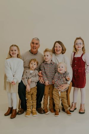 Group of children and adults lined up against a beige wall wearing coordinated casual outfits.