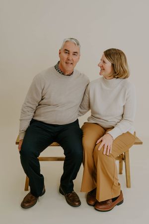 Couple shares a candid moment while sitting together during studio photoshoot.