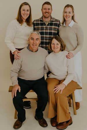 Group of people in coordinated neutral outfits sitting together for a casual photo session.