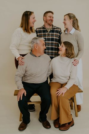 Family members sharing joyful moments during a professional photo shoot on a simple backdrop.