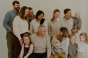 Extended family portrait with multiple generations posing together against neutral background.