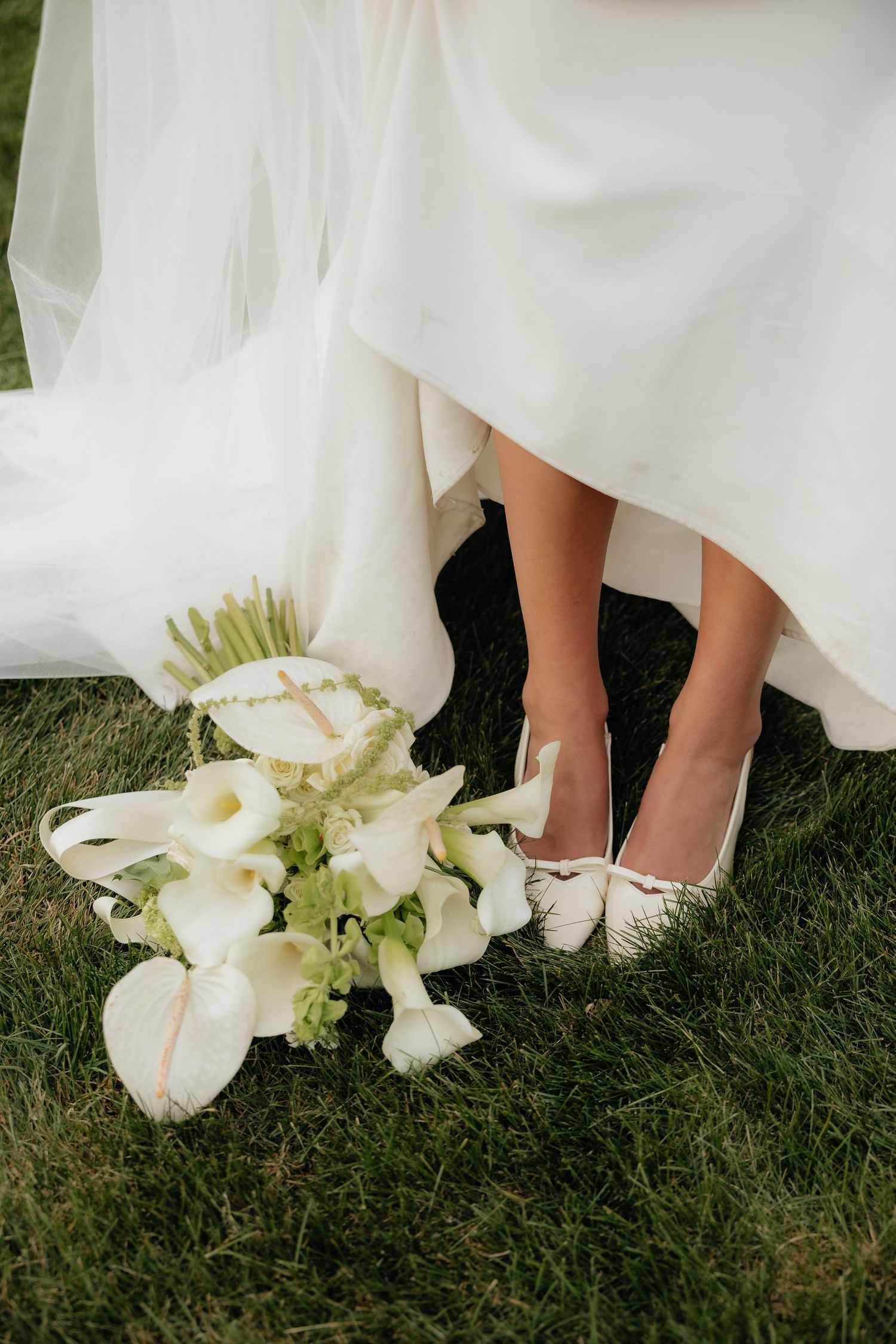 Couple running playfully through grassy hillside during wedding photoshoot.