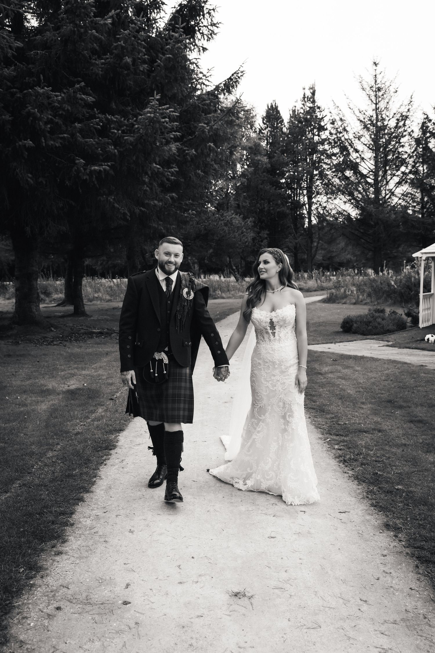 Black and white photo series of a bride and groom walking together along a tree-lined path during their wedding day.