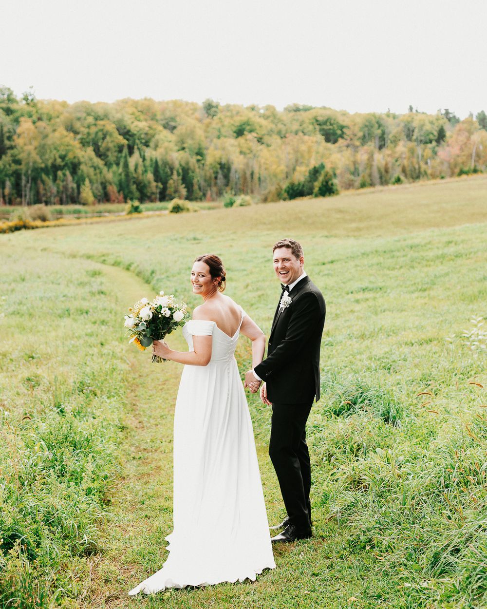 Wedding couple walking through a green meadow on their special day.