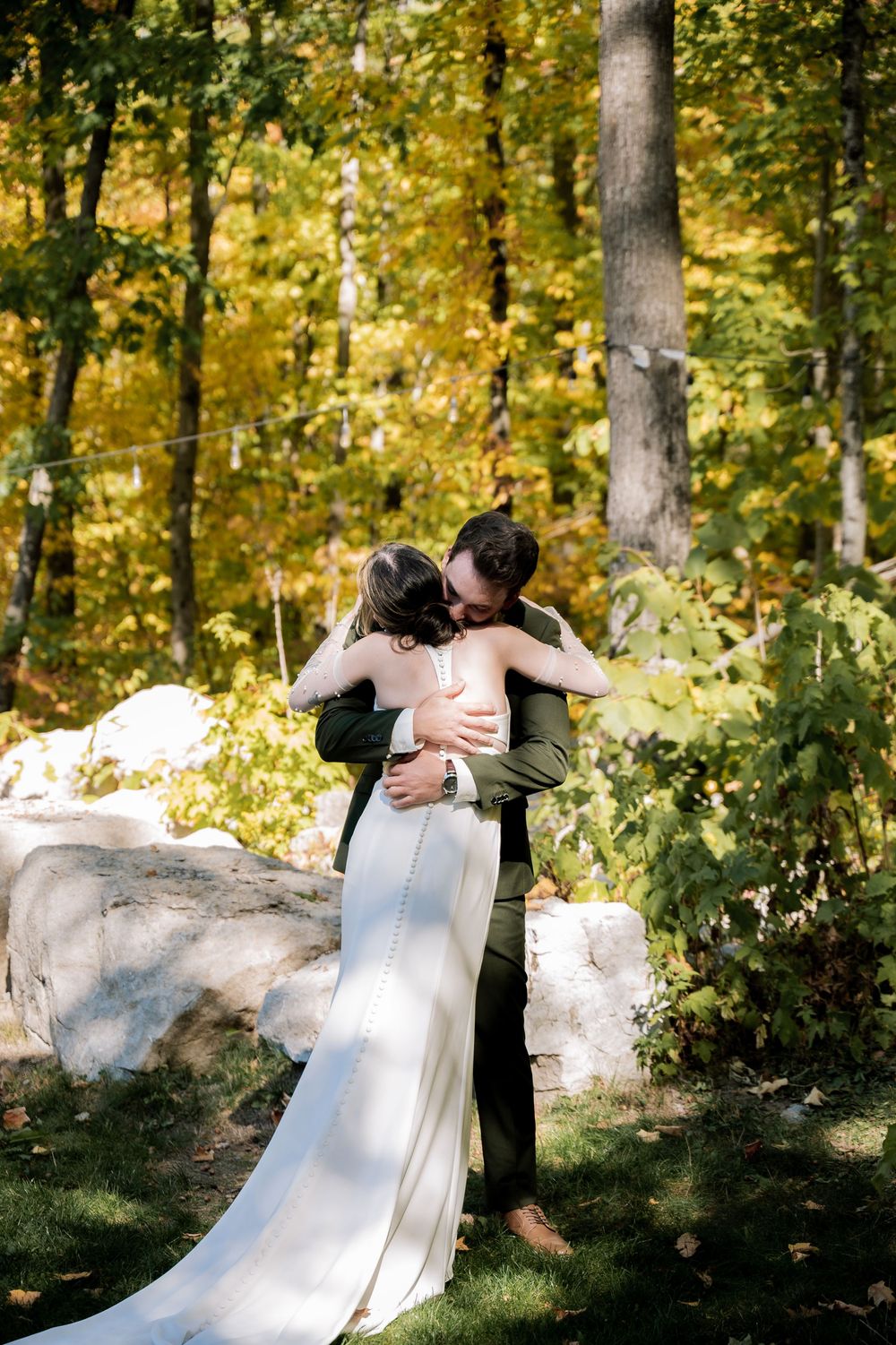 A couple shares a romantic first look moment in a sunlit autumn forest setting.
