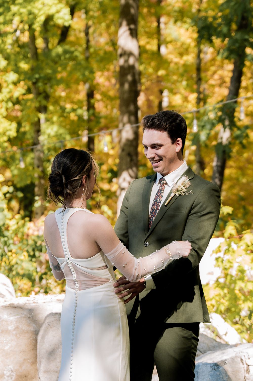 A couple shares a joyful moment during their autumn wedding ceremony surrounded by golden foliage in the woods.