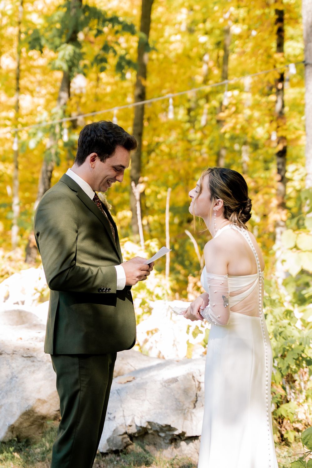 Romantic wedding couple shares intimate moments in a sunlit autumn forest with golden yellow foliage.