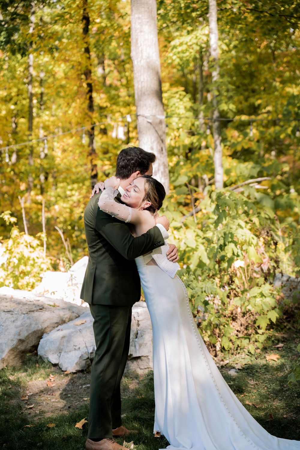 A tender embrace between newlyweds surrounded by golden fall foliage in a wooded setting.