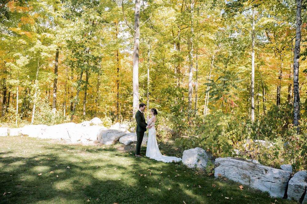 A serene autumn forest wedding scene with natural stone formations and golden leaves.
