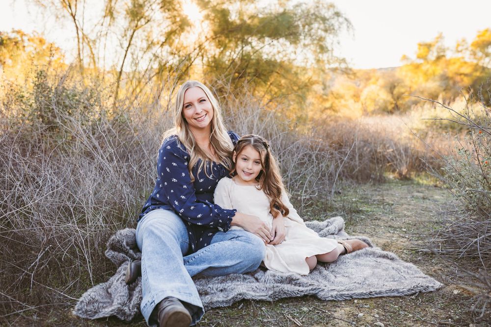 Family poses together on blanket in golden field during sunset photoshoot.