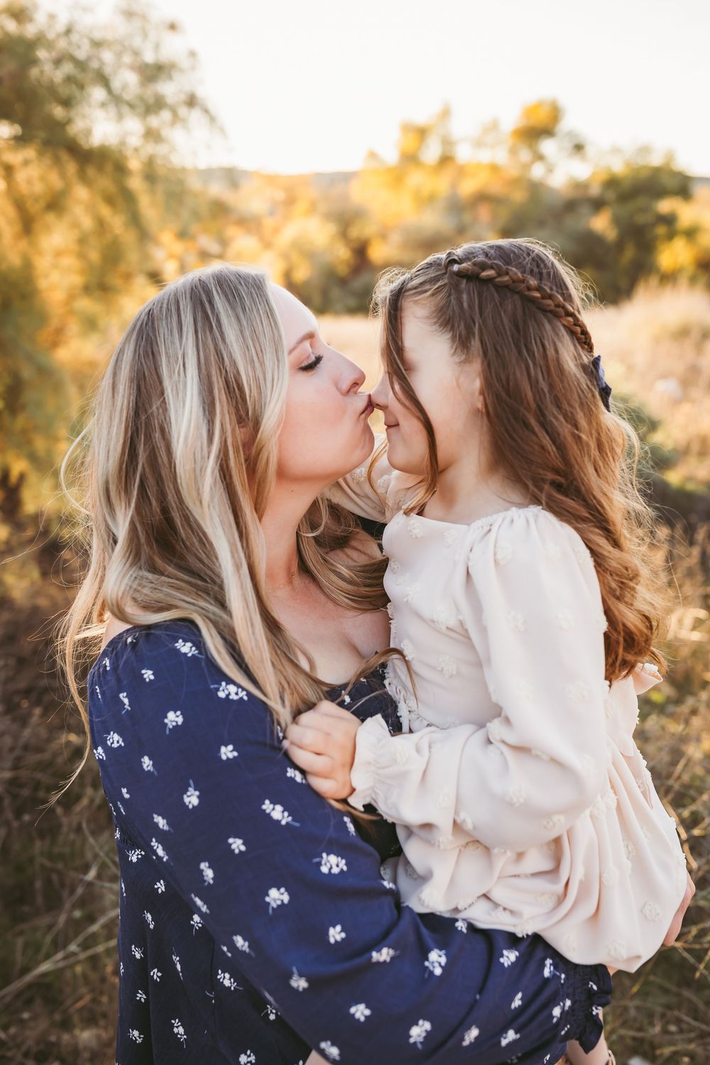 An intimate family moment captured during a sunset photoshoot in a natural outdoor setting.
