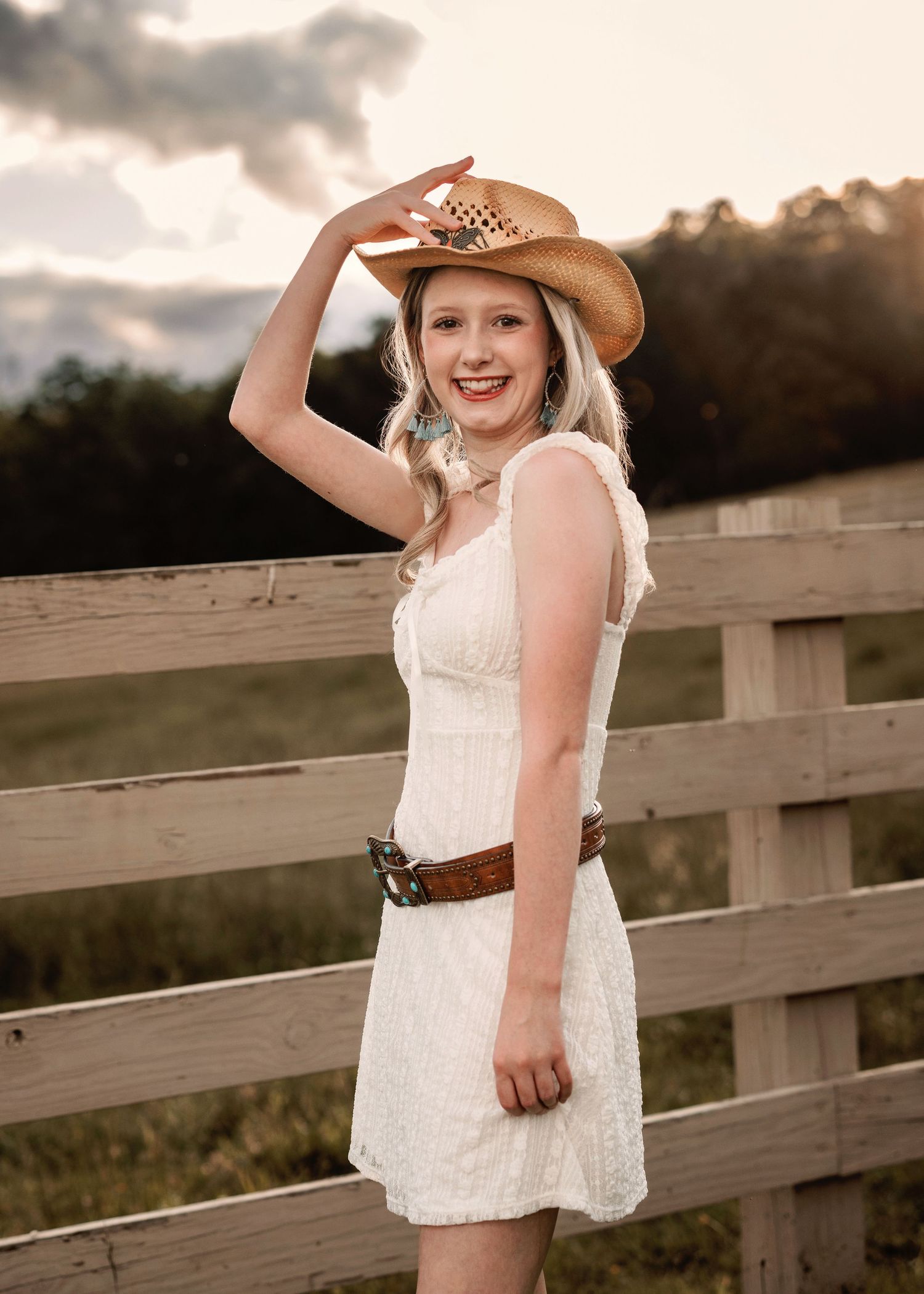 Country style portraits on wooden dock with white lace dress and cowboy hat.