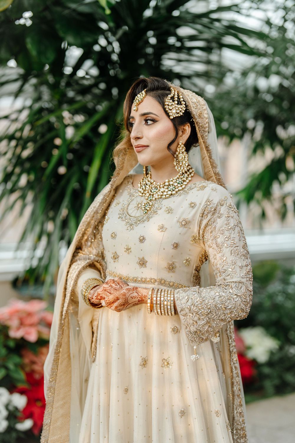 Bride in ivory gold embroidered anarkali with kundan jewelry and dupatta at South Asian wedding.