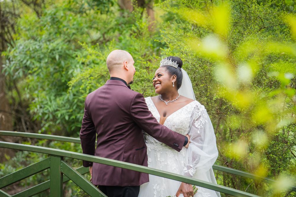 Couple sharing romantic moments in a lush green garden setting during a wedding celebration.