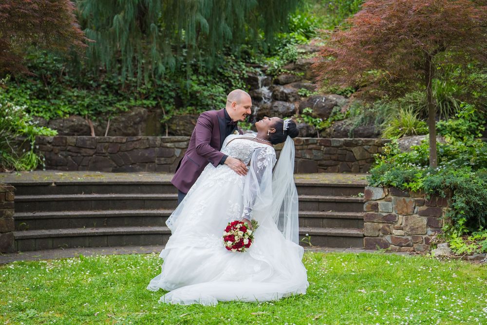 Wedding couple poses together on stone steps surrounded by Japanese maple trees and spring foliage.