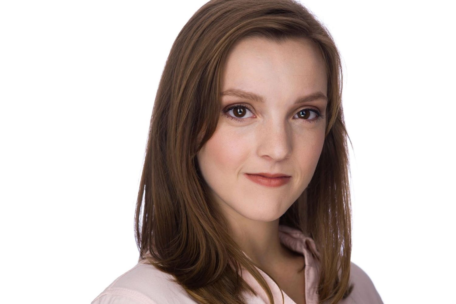 Professional studio portrait of a person with long brown hair wearing a light colored top against a white background.