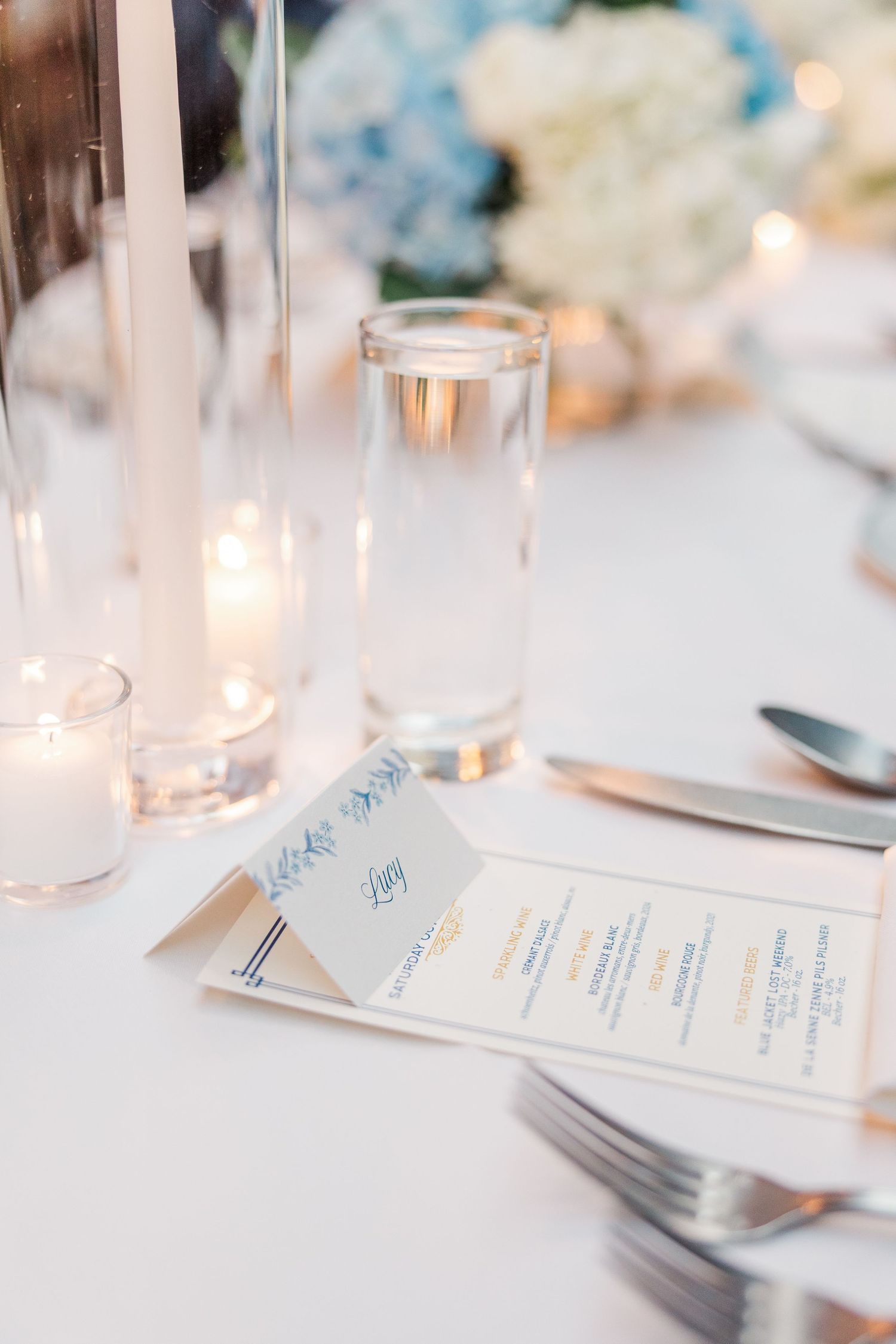 Elegant table setting with lit candles and menu cards creating a romantic dining atmosphere.