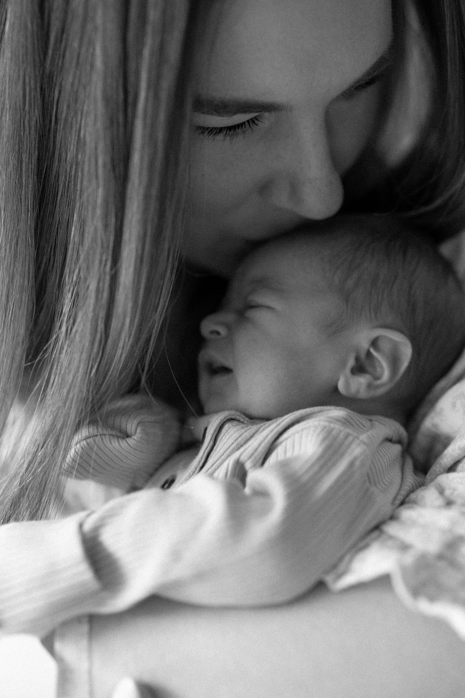 A tender black and white photo series showing a parent and baby in intimate close-up moments.