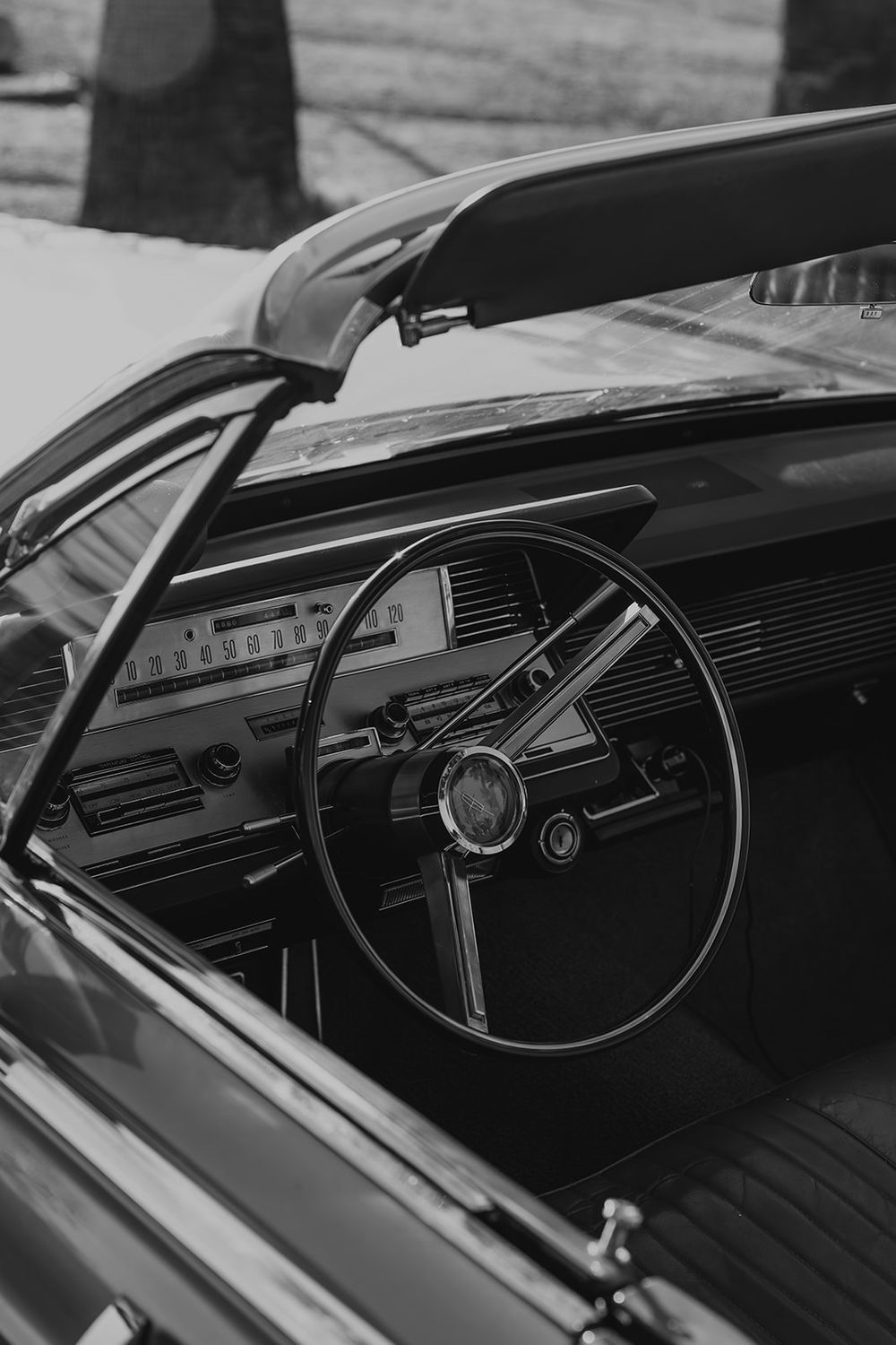 Vintage classic car interior featuring retro steering wheel and dashboard in black and white photography.