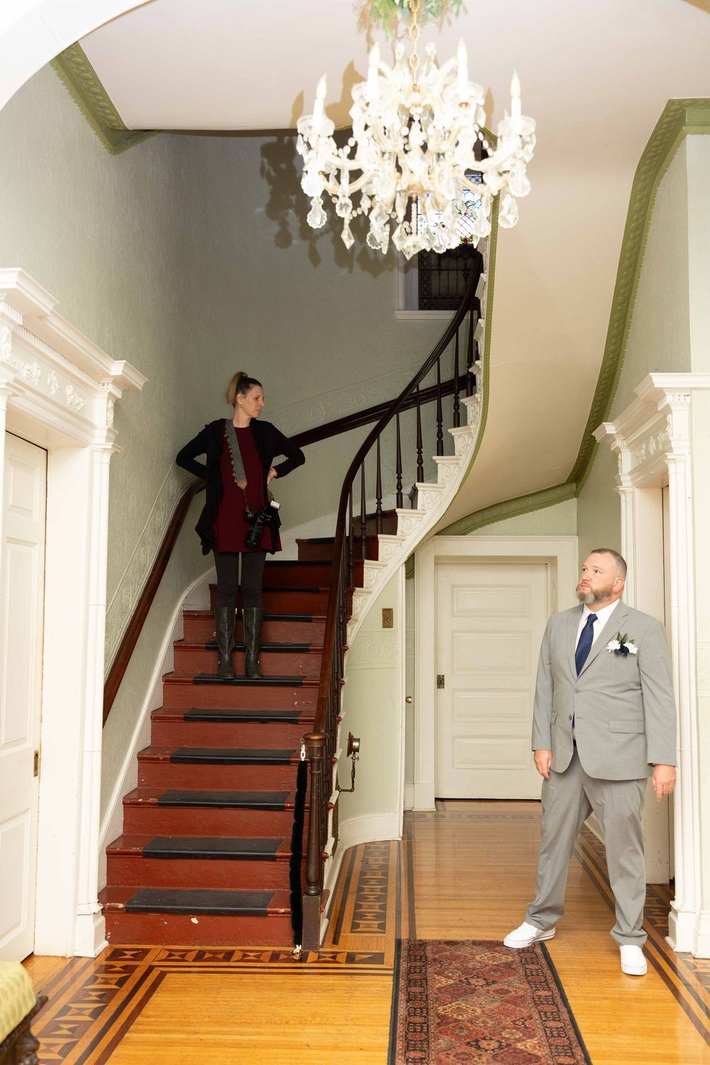 A sequence of five photos showing someone walking down elegant wooden stairs in a bright interior hallway with a chandelier.